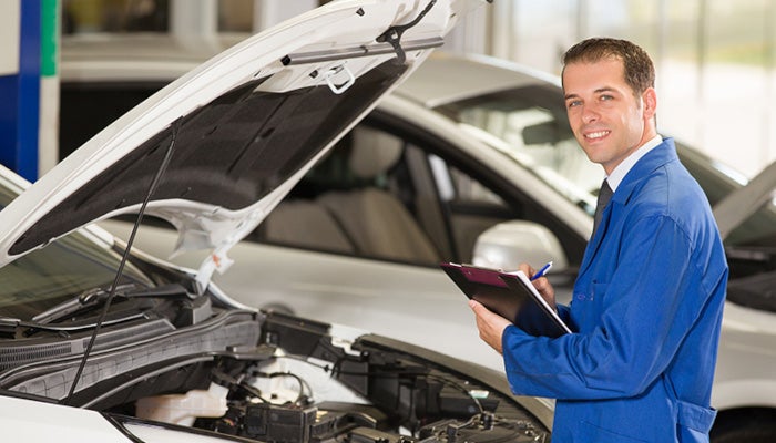 mechanic with clipboard performing car inspection