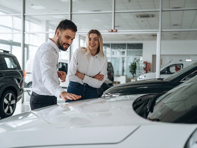 people looking at car in dealership
